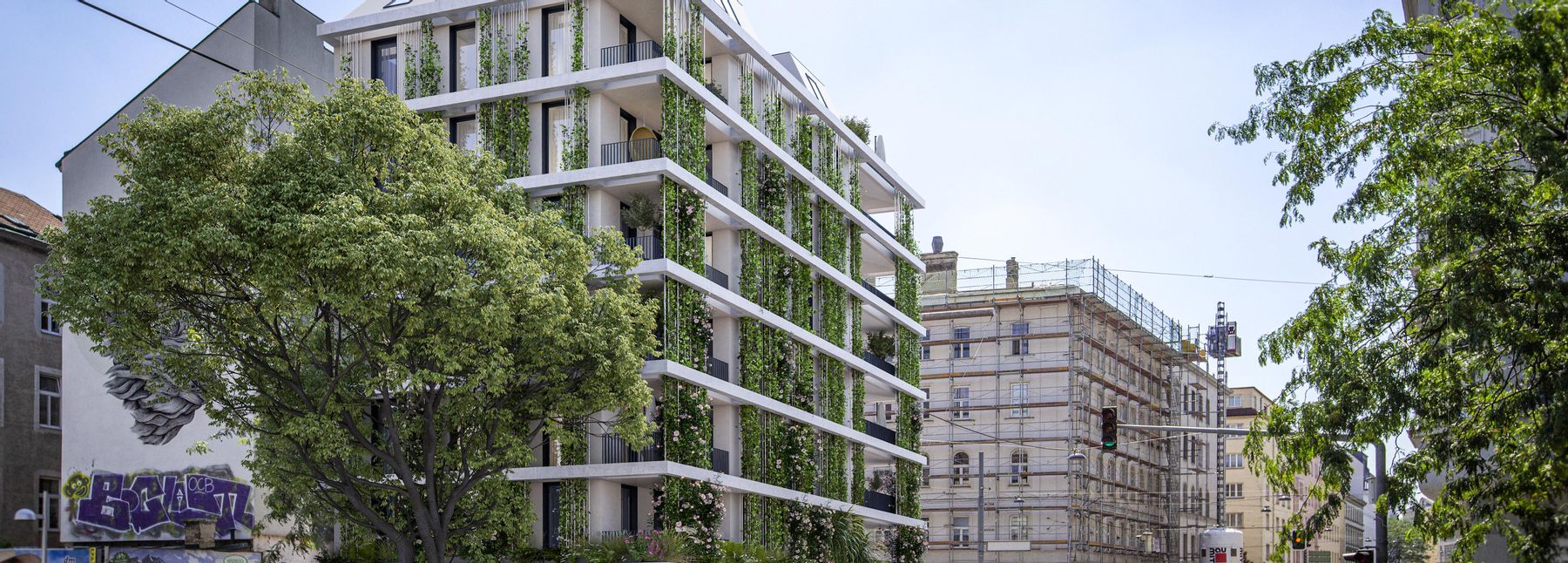 Blick auf die Schönbrunnerstraße mit einem modernen Haus mit Fassadenbegrünung sowie der umliegenden Straße.
