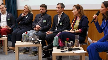 Sechs Personen sitzend bei einer Podiumsdiskussion