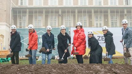 Neun Personen mit Schaufeln in den Händen vor einem Erdhaufen