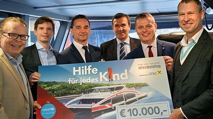 Sechs Personen halten einen Riesenscheck