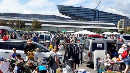 Viele Personen, Marktstände, und Autos auf einem Platz
